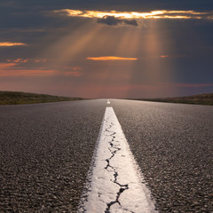 Wall Mural - Driving on empty open road towards the setting sun