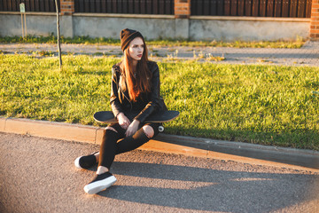 Wall Mural - Beautiful fashion young woman sits on the board with a skateboard