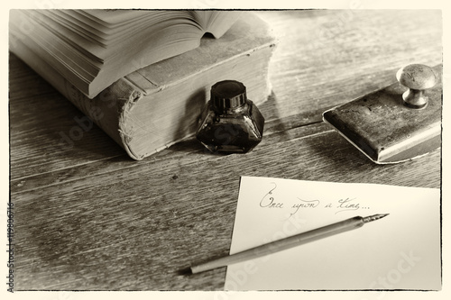 Naklejka nad blat kuchenny Phrase “Once upon a time” handwritten, surrounded with a fountain pen, an ink pot, a blotting paper holder and old books. Selective focus. Grain noise added. Post processed to look like an old photo.