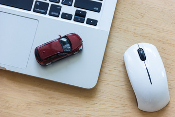 Car model on notebook and mouse on wooden desk