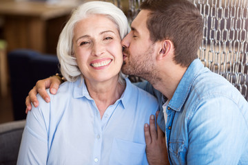 Positive man kissing his grandmother