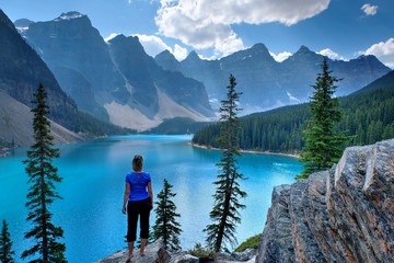 Wall Mural - Woman on cliff at scenic lake and mountains. Moraine Lake in Rocky Mountains. Banff National Park, Alberta, Canada. 