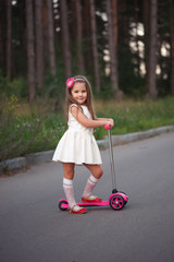 Wall Mural - little girl with scooter on the road