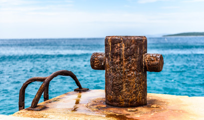 Old rusty steel mooring bollard pole on a pier.