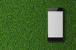 Smart phone with blank screen on green grass background.