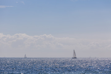 Two yachts with white sails in the blue open sea