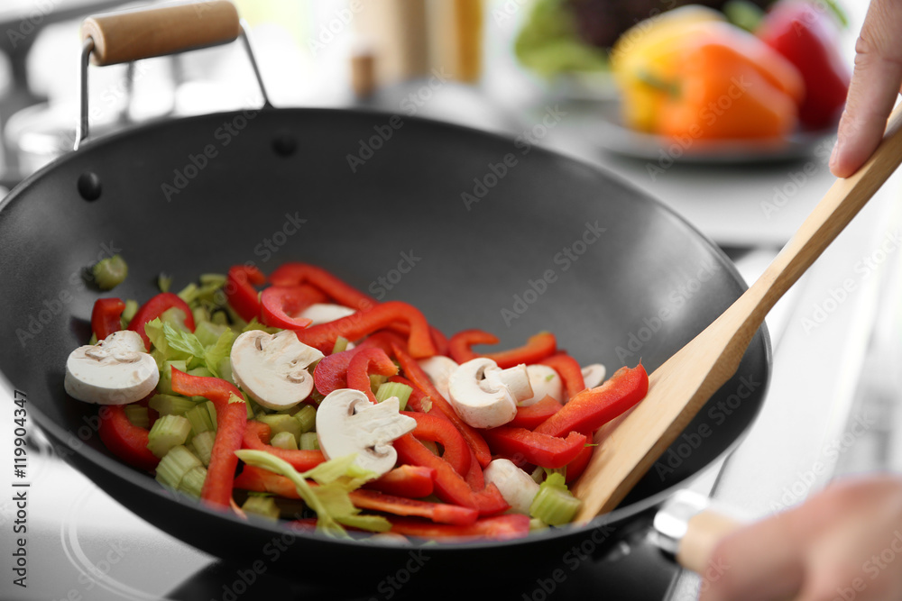 Male hand mixing vegetables in pan closeup