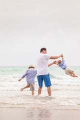 Portrait of father with two sons walking on the ocean beach. Summer vacations by the sea. Outdoors. Happy family.