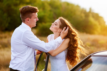 Wall Mural - Happy bride and groom hugging near car