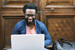 © santypan - Portrait of african man sitting outside with laptop.
