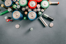 Top View On Portable Batteries On Gray Background, Free Space. Colorful Energy Composition, Variety Of Different Kinds Of Accumulators, Copy Space