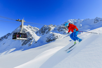 Wall Mural - Skier skiing downhill in high mountains in fresh powder snow. Snow mountain range and cable railway in background. Mt Fort Peak Alps region Switzerland.