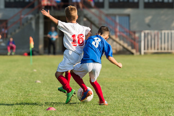 Boys playing football soccer game on sports field