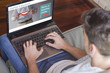 © GENETTICA - Close-up top view of young man at home typing the keyboard of a laptop with dental insurance plan on the screen.