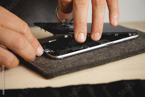 Fotografía Man uses vacuum plug and plastic opener to change screen from broken phone, his