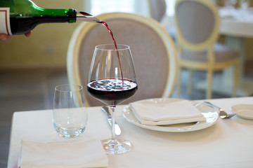 served table restaurant wine being poured into glass, white tablecloth, plates and cutlery