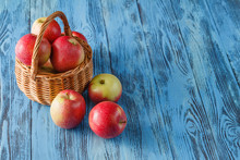 Wicker Basket Full Of Red Gala Apples On Rustic Wooden Backgroun