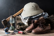 still life photography : axe, compass, hunter hat, jeans, lamp, leather shoe, map, pocket knife, shirt, stump, sunglasses in adventurer concept
