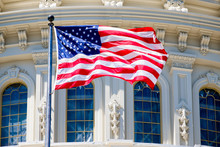 The American Flag Waves In Front Of The Capitol Building In Washington D.C.