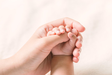 Baby hand holding finger mom on vintage tone. (Selected focus)