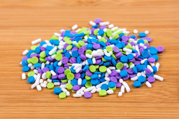 Sticker - Multicolored candy sprinkles isolated on wood background