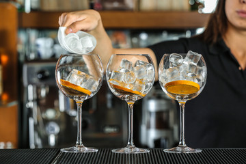 Poster - Woman hands adding ice into cocktail on bar counter