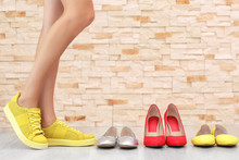 Woman Choosing Shoes On Brick Wall Background