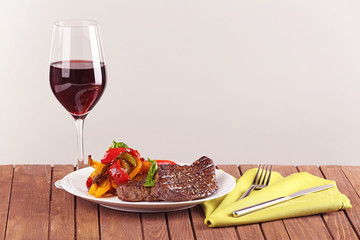 Poster - Delicious steak with vegetables and glass of wine on wooden table