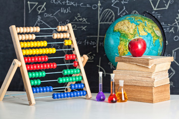 Wall Mural -  abacus, chemical test tubes, apple on old books and slate blackboard. school and learning concept. nobody around, landscape format.