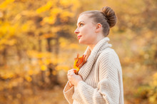 Beautiful Woman In Autumn Park Holding Yellow Leaf