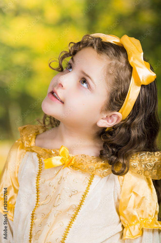 Cute little girl wearing beautiful yellow dress with matching head band,  posing for camera, green forest background Stock Photo | Adobe Stock