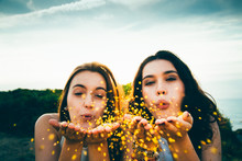 Funny Girls Blowing Golden Glitter Over A Cliff