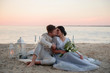 © ronedya - Young couple in love outdoor. Young bride and groom posing at sunset on the beach. young couple on the beach. young couple relaxing at sunset. young couple relaxing on the beach