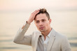 © ronedya - young handsome man in a white suit near the sea at sunset. young handsome groom on the beach. Close-up