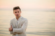 © ronedya - young handsome man in a white suit near the sea at sunset. young handsome groom on the beach. Close-up