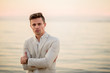 © ronedya - young handsome man in a white suit near the sea at sunset. young handsome groom on the beach. Close-up