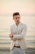 © ronedya - young handsome man in a white suit near the sea at sunset. young handsome groom on the beach. Close-up