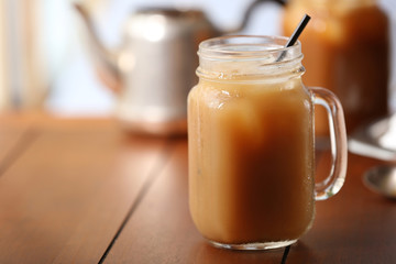 Wall Mural - Iced coffee in glass jar with straw on brown wooden table