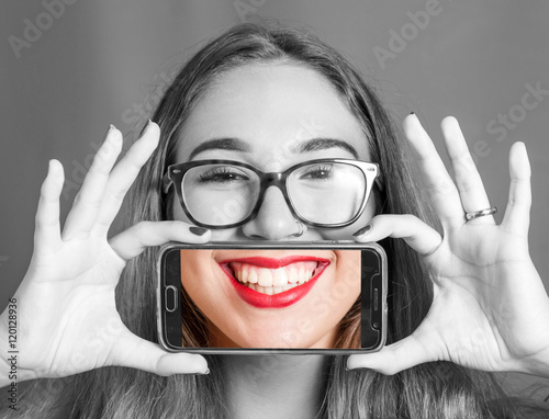 Fotografia ragazza con smartphone che si scatta una foto al proprio sorriso