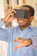 Man wearing blue shirt testing vitrual reality mobile device, holding glasses in front of eyes and smiling