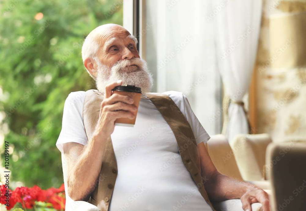 Elderly man sitting with coffee  in a armchair