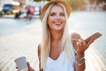 portrait of a girl in hat holding cup and smartphone