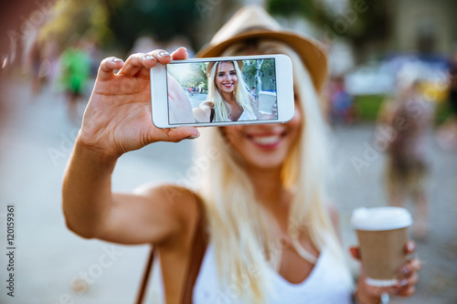 Cuadros en Lienzo Young smiling girl making selfie while standing on the street