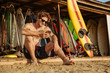 Young handsome surfer sitting and using smartphone outdoors