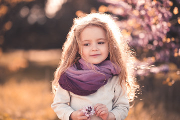 Wall Mural - Cute baby girl 3-4 year old holding flower wearing stylish clothes outdoors.