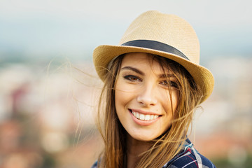 closeup portrait of beautiful young blonde woman in brown fedora on windy autumn day