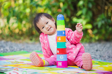 An Outdoor Picture Of The Baby Try To Make A Tower Blocks. This Activity Is Good For Improve Hand Function And Fine Motor Skills In Children.