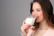 © kazanovskyiphoto - Lady drinking milk from a wine glass. Close up. Gray background