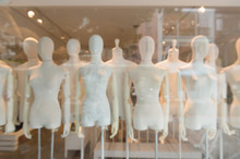 De Focused/Blur Image Of Boutique Window With Dressed Mannequins. Boutique Display Window With Mannequins In Fashionable Dresses. Toned Image.