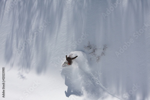 Fotografie, Obraz Snowboarder Carving a Powder Turn in a Wall of Fresh Powder Snow